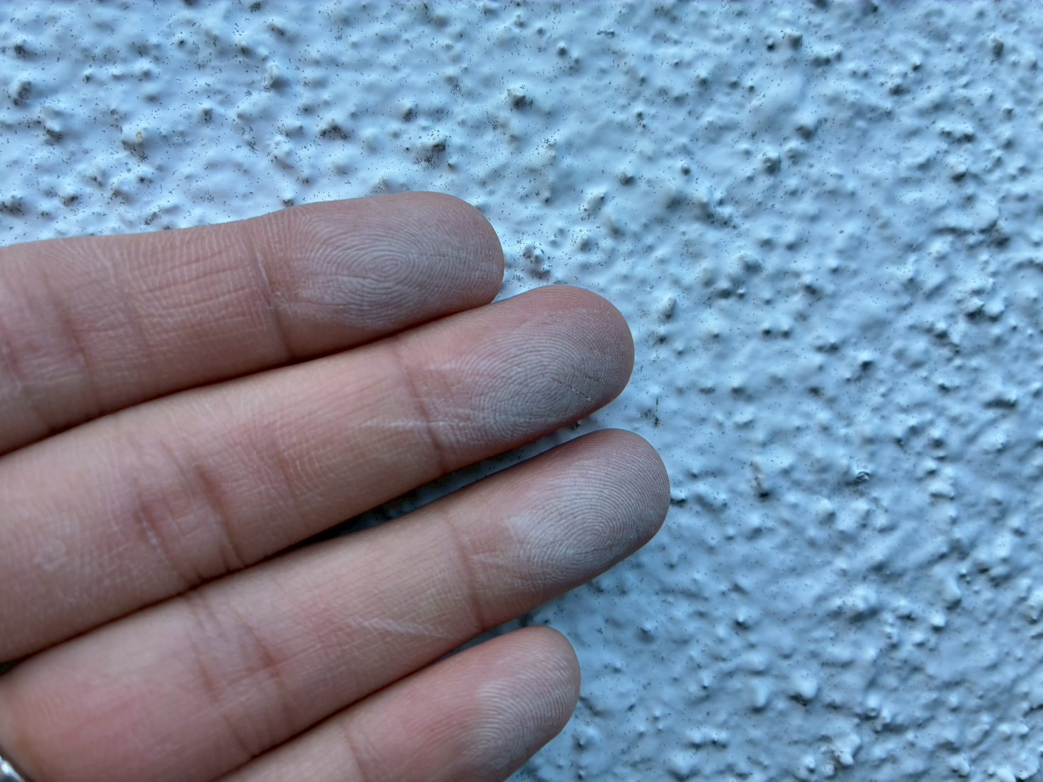 外壁を触るとチョーキングにより古い塗膜が手に付着した